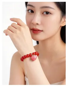 Close-up detail of the natural red agate bead bracelet featuring a cute pink peach pendant.