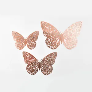 Détail rapproché des stickers muraux papillons ajourés or rose au motif floral élégant.