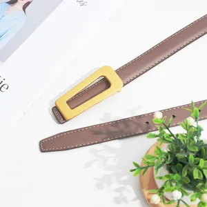 Detailed shot of women's brown leather belt with elegant gold geometric metal buckle close-up.