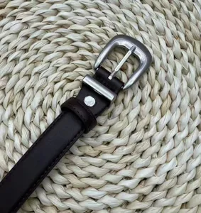 Close-up detail of a dark brown leather belt with a stylish silver metal pin buckle.