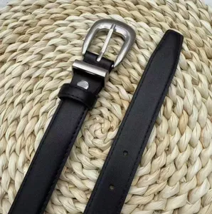 Close-up of black leather belt with silver pin buckle, textured strap detail for trousers.