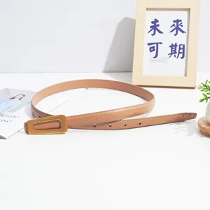 Women's minimalist leather belt with unique gold geometric buckle, elegant tan waist accessory.