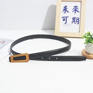 Detailed view of women's black leather belt featuring a sleek modern gold-tone geometric buckle.