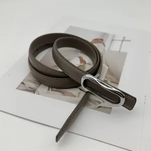 Gros plan détaillé d'une ceinture en cuir minimaliste pour femme avec boucle argentée élégante.