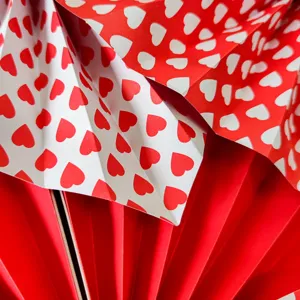 Close-up detail of red and white heart pattern paper fan flowers for Valentine's Day wedding decor.