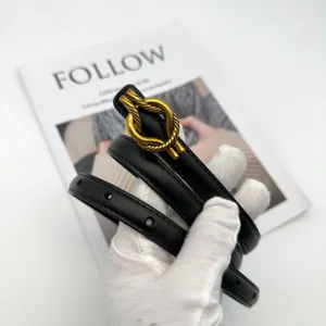 Close-up detail of womens black leather belt featuring a chic golden knot metal buckle.