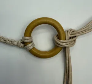 Close-up detail of bohemian handmade braided waist belt with wooden ring and tassel design.