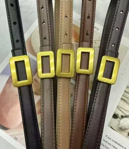 Close-up detail of slim leather belts with gold rectangular buckles in various elegant colors.