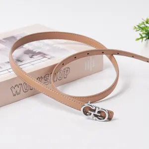 Close-up detail of women's slim leather belt with silver-tone metal buckle on neutral prop.