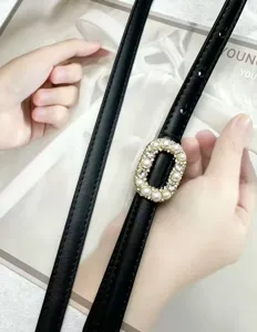 Black leather belt detail featuring an elegant pearl and rhinestone oval buckle for women.
