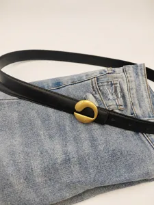 Black leather belt detail with unique gold metal buckle, stylish accessory for women jeans.