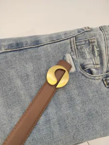 Close-up of a stylish brown leather women belt featuring a unique gold metal buckle design.