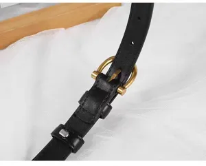 Detailed view of women's black slim leather belt with vintage brass buckle, elegant design.