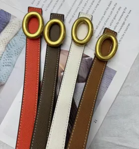 Dettaglio di eleganti cinture in pelle da donna con fibbie metalliche dorate e cuciture.