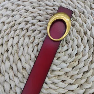 Detail van rode lederen riem met gouden ovale gesp, stijlvol vintage accessoire voor dames.