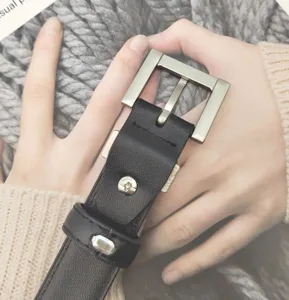 Black leather belt detail shot with silver metal square buckle and rivet design.
