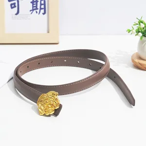 Closeup of minimalist brown leather belt with gold rose metal buckle, elegant fashion accessory.