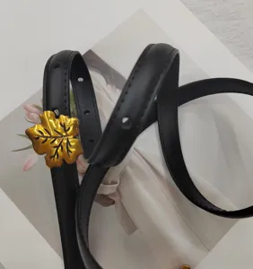 Black thin leather belt with gold leaf buckle, elegant decorative accessory for dresses.