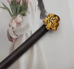 Elegant dark brown leather belt detail with a shiny gold leaf buckle for women outfits.