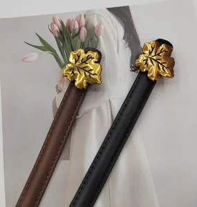 Detailed close-up view of women's thin leather belt featuring a chic gold maple leaf buckle.