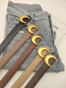 Detail view of stylish women's thin leather belts with elegant gold crescent moon metal buckles.