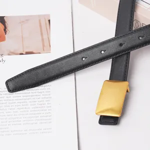 Close-up detail shot of a stylish women's black leather belt featuring a sleek rectangular gold buckle.