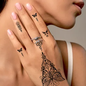 Gros plan de tatouages éphémères papillons noirs exquis sur la main d'une femme.