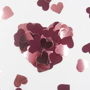 Close up view of heart confetti details, showing shiny rose gold and dark red paper pieces.