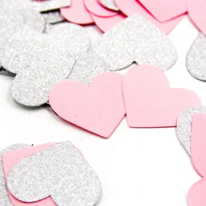 Close-up view of shimmering silver and pink heart confetti scattered for party decor.