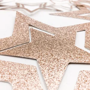 Close-up detail of rose gold glitter star cutouts, perfect for festive party decor.