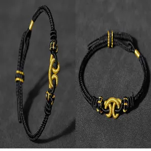 Detailansicht eines handgemachten schwarz geflochtenen Seilarmbands mit Goldelementen, ethnisch.