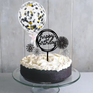 Detailed view of birthday cake topper set including balloon, black sign and paper fans.