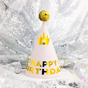 Detailed shot of a pink paper birthday party hat with gold crown and glitter pompom.