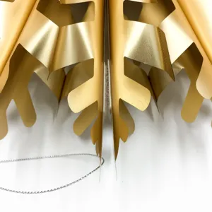 Gold metallic paper fan detail, close up view of hollowed snowflake hanging party decor.