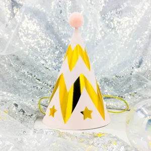 Detail view of a pink birthday party hat with gold chevron pattern and fluffy pom-pom top.