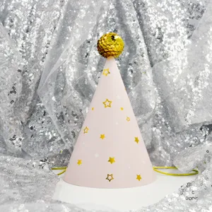 Close-up detail of cute pink cone birthday party hat with gold stars and sequin pom-pom.