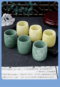 Close-up of natural Lantian jade tea cups showing elegant green and yellow stone texture details.