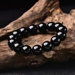 Dettaglio ravvicinato di un bracciale in ossidiana nera con perline rotonde lisce e lucide.