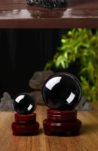 Close-up detail view of smooth polished black obsidian crystal spheres on wooden stands.