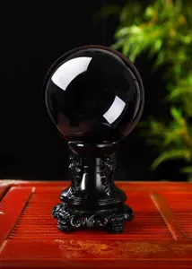 Detailed close-up of a polished black obsidian crystal sphere ornament on a carved stand.