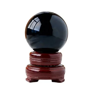 Black obsidian crystal ball with wooden base, polished sphere for feng shui decor.