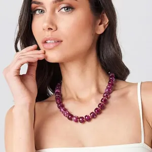 Vue de détail du collier élégant de perles mauves avec des accents dorés portés par modèle.