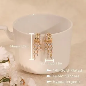 Primo piano di orecchini pendenti multustrato placcati in oro con zirconi cubici luminosi.