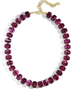 Elégant collier de perles pourpres avec espaceurs en laiton plaqué or et fermoir chic.