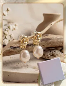 Close-up detail of brass gold-plated knotted earrings with dangling baroque pearls, elegant ins style.
