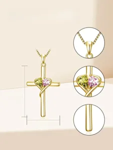 Close-up detail view of gold cross necklace featuring sparkling double heart cubic zirconia stones.