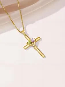Close-up detail of the gold cross pendant necklace featuring sparkling green and pink heart gems.