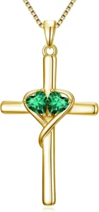 Exquisite gold cross necklace detail view with twin green heart stones on a delicate chain.