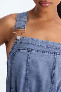 Women denim jumpsuit detail shot, casual blue bib overalls with metal hardware and pocket.