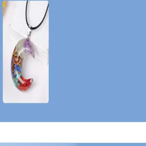 Gros plan détaillé du pendentif croissant en pierres concassées colorées et résine.
